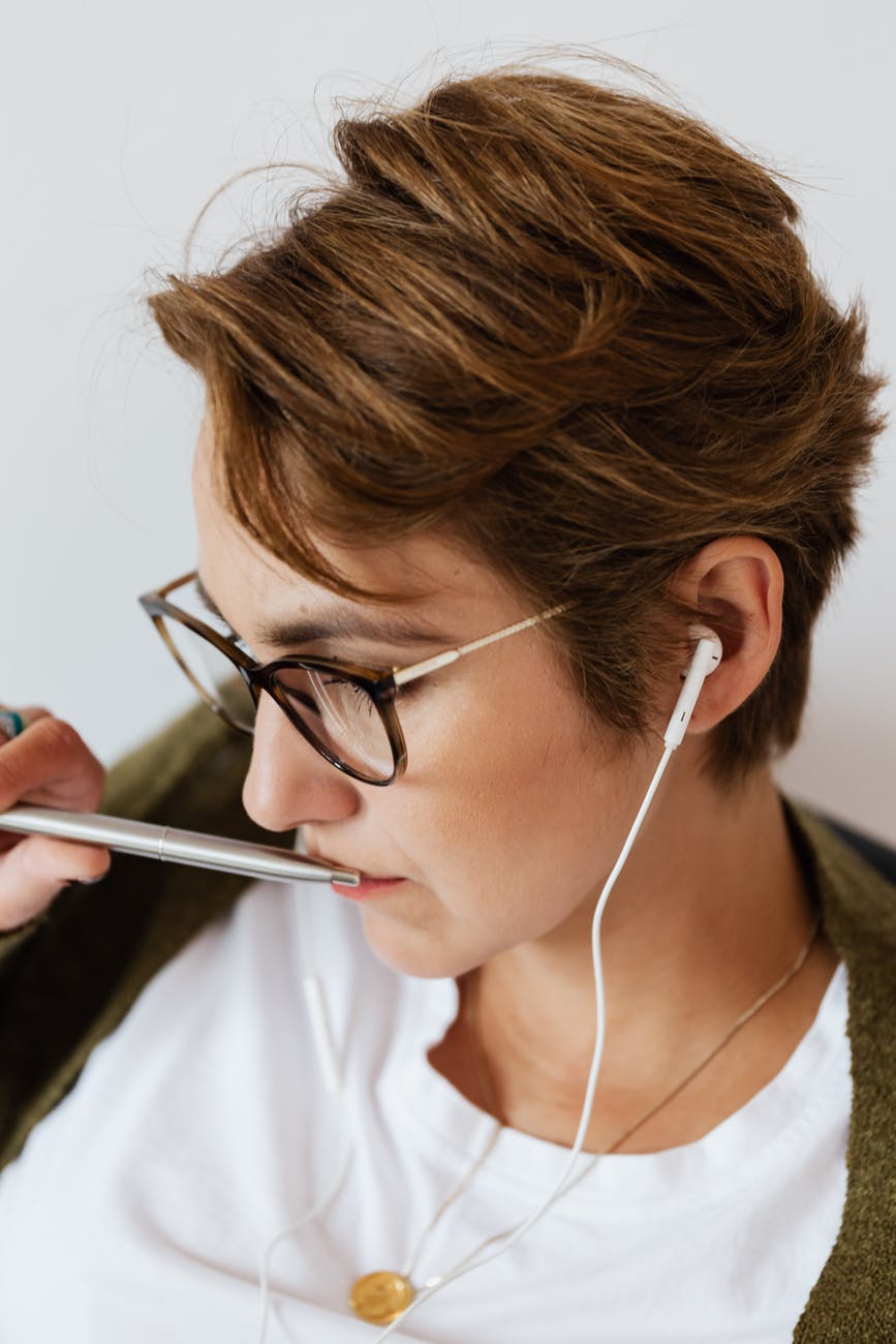 concentrated woman in casual wear listening to music in earphones